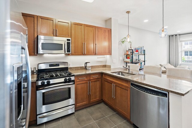 30 Freedom Way Unit 302, Jersey City, NJ 07305 - kitchen with appliances with stainless steel finishes, a peninsula, brown cabinetry, light stone counters, and dark tile patterned floors