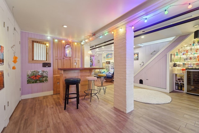 bar with beverage cooler, hardwood / wood-style floors, and ornate columns