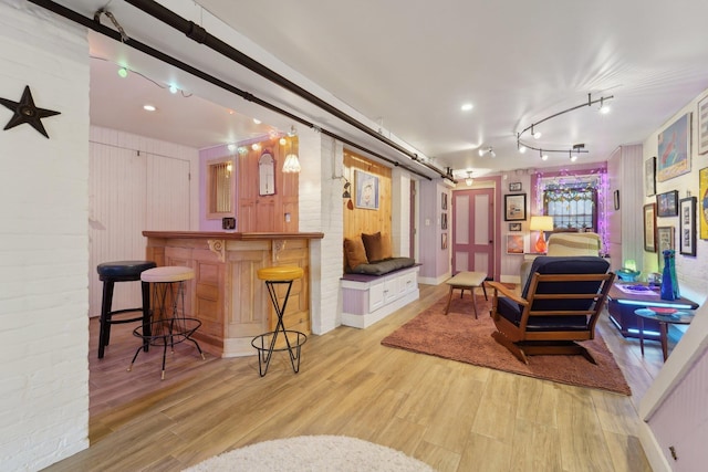 interior space with rail lighting, a barn door, indoor bar, and light wood-type flooring