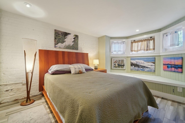 bedroom with brick wall and hardwood / wood-style floors