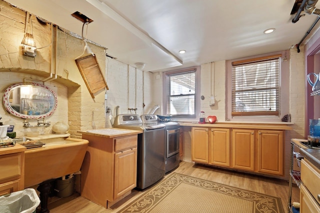 clothes washing area with independent washer and dryer and light hardwood / wood-style flooring