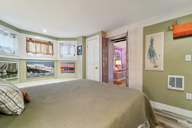 bedroom with hardwood / wood-style floors and heating unit