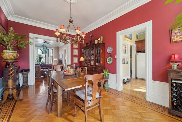 dining space with light parquet floors, ornamental molding, and a notable chandelier