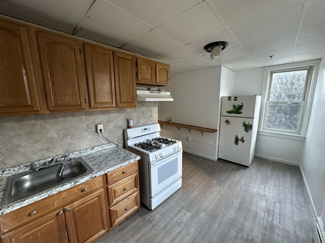 2512 Central Ave, Union City, NJ 08070 - kitchen with white appliances, a paneled ceiling, under cabinet range hood, brown cabinets, and a sink