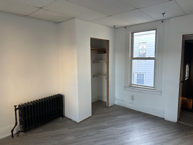2512 Central Ave, Union City, NJ 08070 - unfurnished bedroom with radiator heating unit, a paneled ceiling, wood finished floors, a closet, and baseboards