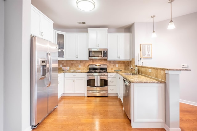 kitchen with light wood finished floors, visible vents, appliances with stainless steel finishes, a sink, and backsplash