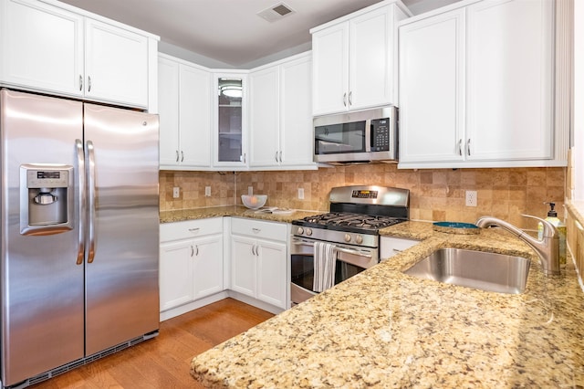 kitchen with appliances with stainless steel finishes, a sink, visible vents, and decorative backsplash