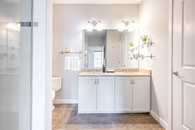 bathroom featuring toilet, double vanity, baseboards, and a sink