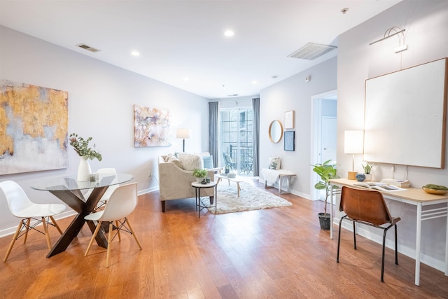 living room with light wood-style flooring, visible vents, and baseboards