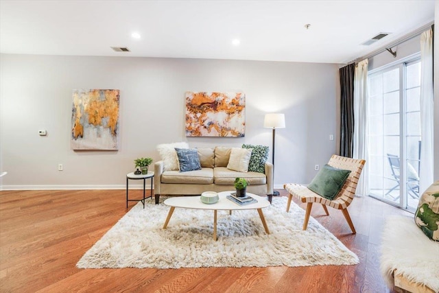 living room featuring baseboards, visible vents, wood finished floors, and recessed lighting