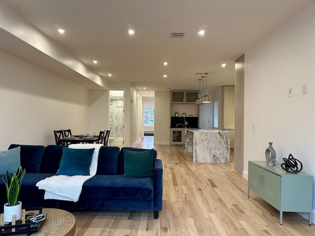 living area with visible vents, recessed lighting, beverage cooler, and light wood-style floors