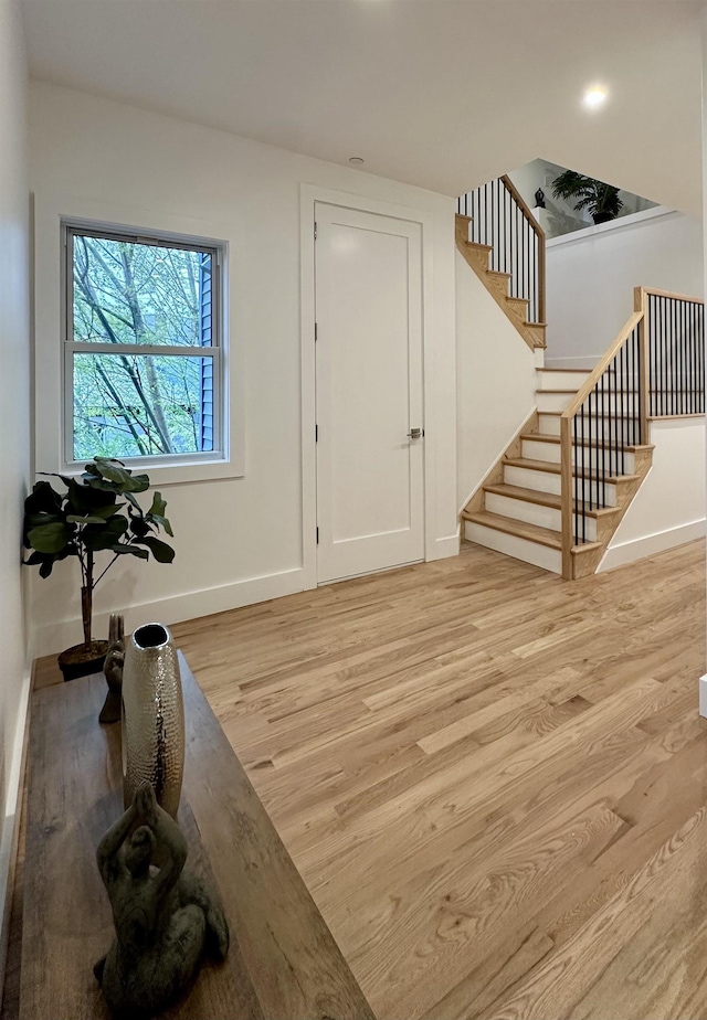 entryway featuring light wood-type flooring, baseboards, and stairs