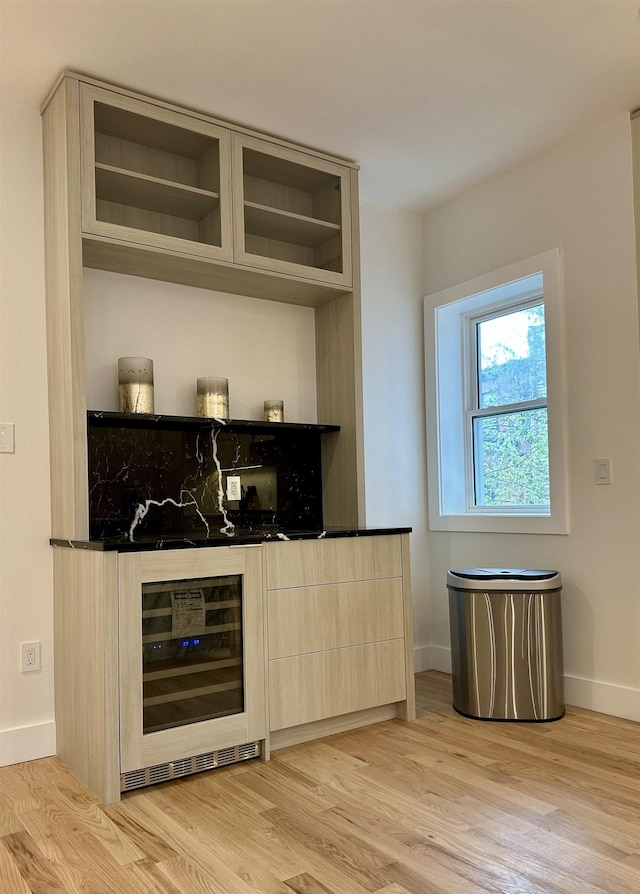 bar featuring wine cooler, baseboards, a dry bar, and light wood-style flooring