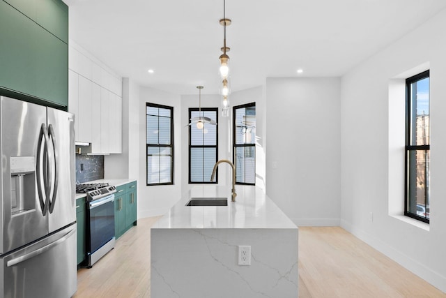 kitchen featuring tasteful backsplash, light stone counters, hanging light fixtures, stainless steel appliances, and white cabinets