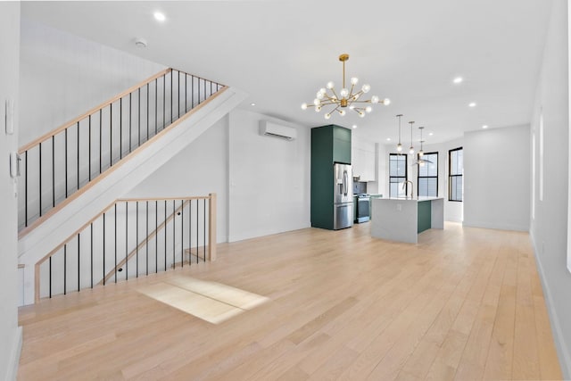 living room featuring a chandelier, a wall mounted AC, sink, and light hardwood / wood-style flooring