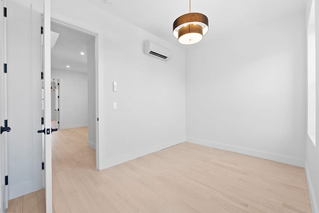 unfurnished room featuring a wall mounted AC and light wood-type flooring