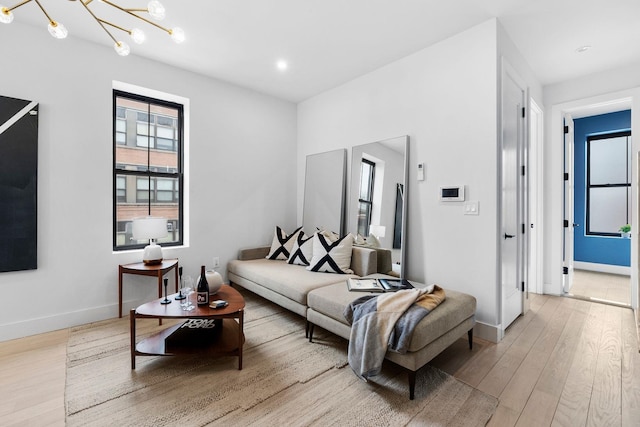 living room featuring a notable chandelier, recessed lighting, baseboards, and light wood finished floors