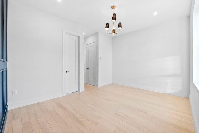 unfurnished room with a notable chandelier and light hardwood / wood-style floors