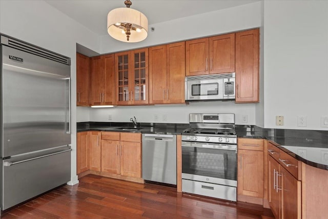 389 Washington St Unit 34E, Jersey City, NJ 07302 - kitchen with stainless steel appliances, dark countertops, glass insert cabinets, dark wood-style flooring, and brown cabinets