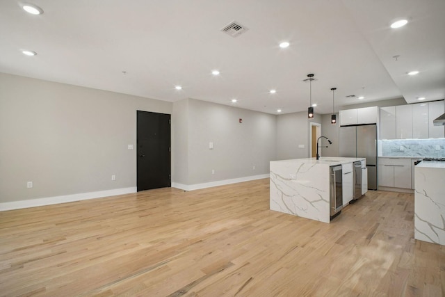 211 Summit Ave Unit 1, Jersey City, NJ 07304 - kitchen featuring an island with sink, modern cabinets, light wood-style flooring, white cabinets, and backsplash