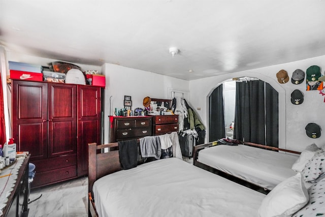 bedroom featuring arched walkways and marble finish floor