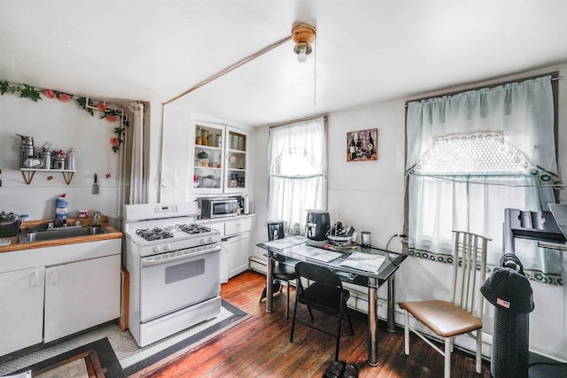 kitchen with light wood-style flooring, a sink, white cabinets, stainless steel microwave, and white gas range