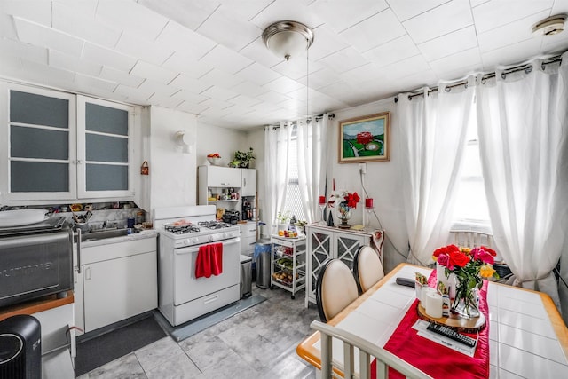 kitchen featuring white cabinetry, glass insert cabinets, white gas range oven, and a sink