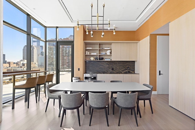 dining space with light wood-style flooring, a view of city, and a wall of windows