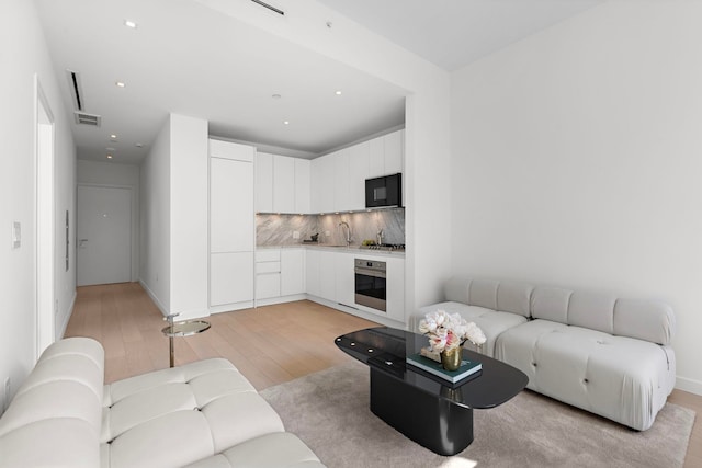 living area featuring recessed lighting, visible vents, and light wood-type flooring