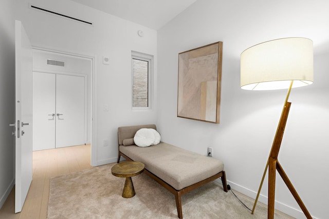 sitting room with wood finished floors, visible vents, and baseboards