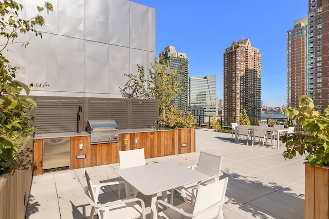 view of patio with outdoor dining space, a view of city, area for grilling, and an outdoor kitchen