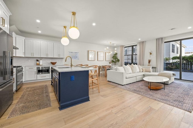 kitchen featuring blue cabinetry, a kitchen bar, sink, premium appliances, and white cabinets