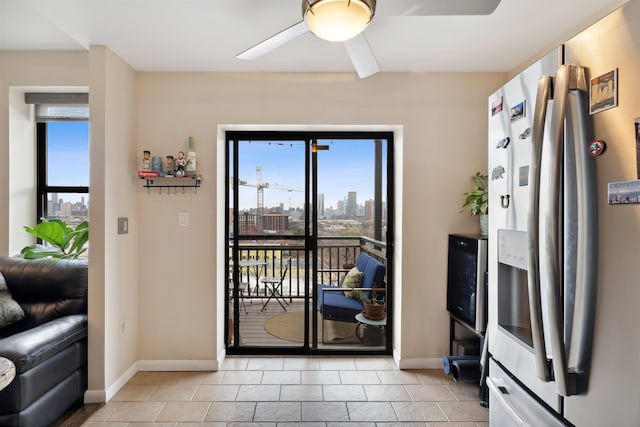 doorway with ceiling fan, light tile patterned floors, and a healthy amount of sunlight