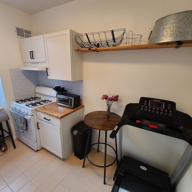 kitchen featuring under cabinet range hood, white range with gas stovetop, visible vents, and white cabinets