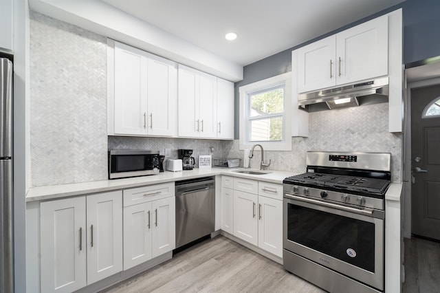 kitchen with white cabinetry, stainless steel appliances, sink, and light hardwood / wood-style flooring