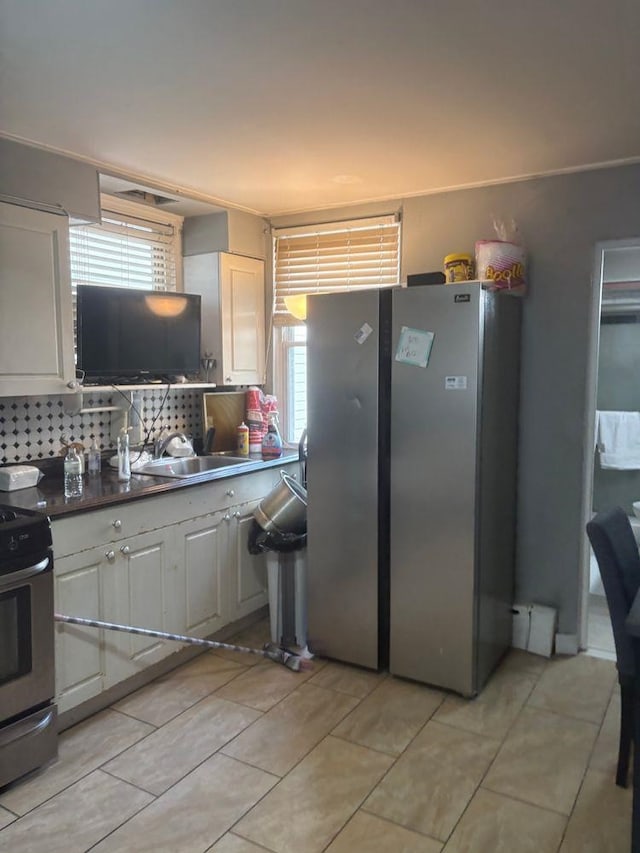 6113 Washington St, West New York, NJ 07093 - kitchen featuring appliances with stainless steel finishes, decorative backsplash, light tile patterned floors, white cabinets, and dark countertops
