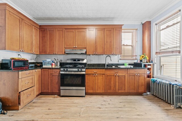6113 Washington St, West New York, NJ 07093 - kitchen with stainless steel range with gas stovetop, radiator, under cabinet range hood, an ornate ceiling, and light wood finished floors