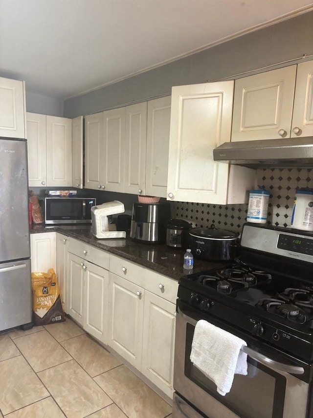 6113 Washington St, West New York, NJ 07093 - kitchen featuring stainless steel appliances, light tile patterned floors, tasteful backsplash, white cabinets, and under cabinet range hood
