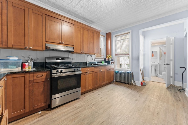 6113 Washington St, West New York, NJ 07093 - kitchen with stainless steel gas range oven, radiator, under cabinet range hood, backsplash, and ornamental molding