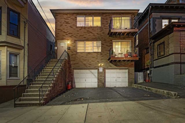 419 16th St, Union City, NJ 07038 - view of front facade featuring brick siding, a garage, asphalt driveway, stairway, and a balcony