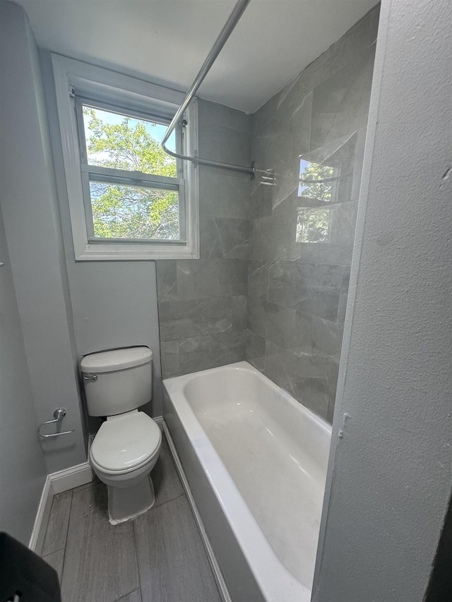 bathroom with tiled shower / bath combo and toilet