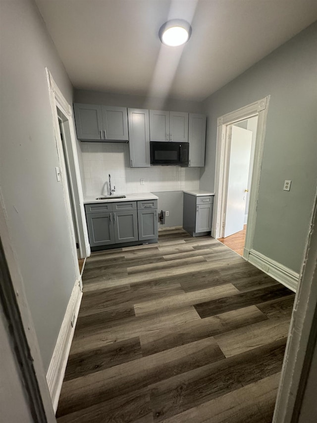 kitchen with gray cabinetry, dark wood-type flooring, backsplash, and sink