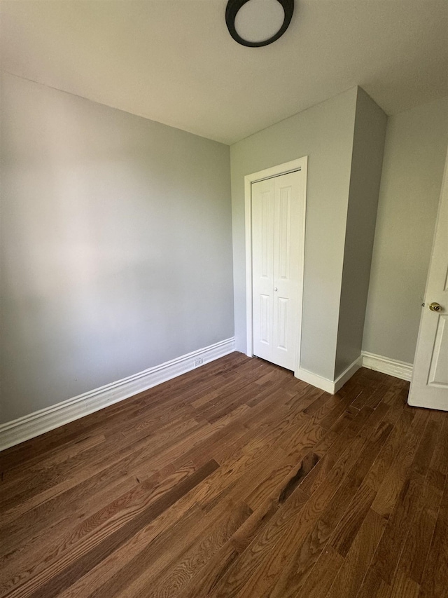 unfurnished bedroom featuring a closet and dark hardwood / wood-style floors