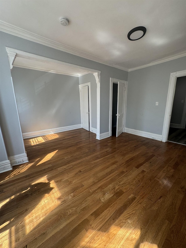 spare room with ornamental molding and dark wood-type flooring