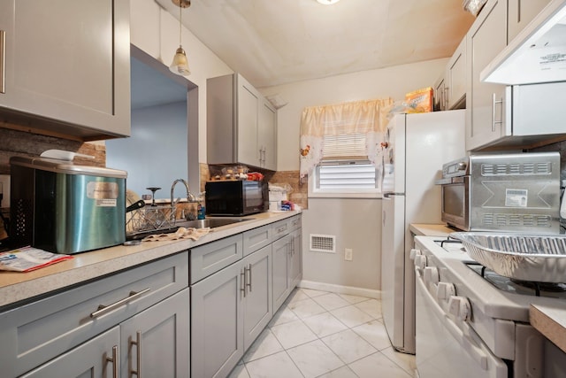 kitchen featuring tasteful backsplash, light tile patterned floors, gray cabinets, pendant lighting, and sink