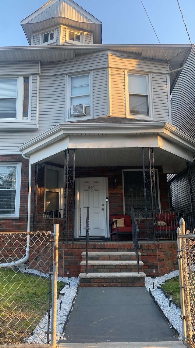 view of front of home featuring a porch, fence, and cooling unit