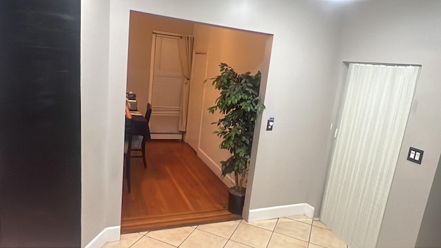 hallway featuring light tile patterned flooring, baseboards, and baseboard heating