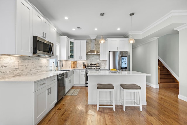 1163 Summit Ave Unit 2, Jersey City, NJ 07307 - kitchen with stainless steel appliances, wall chimney exhaust hood, a kitchen island, a kitchen bar, and white cabinetry