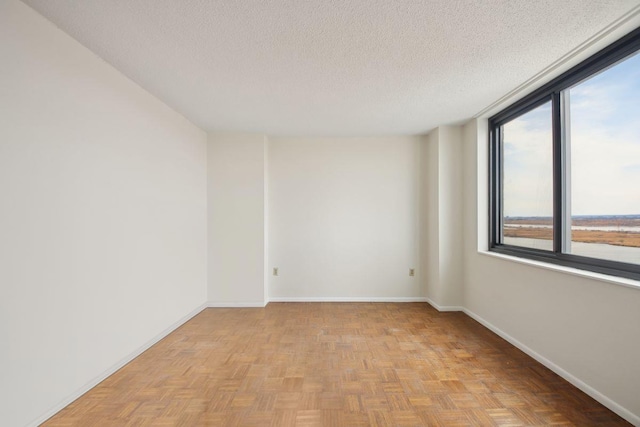 spare room with a textured ceiling and baseboards