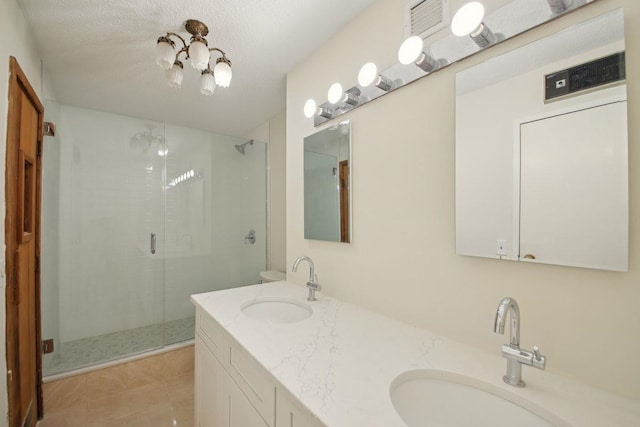 bathroom with a sink, a shower stall, a textured ceiling, and double vanity